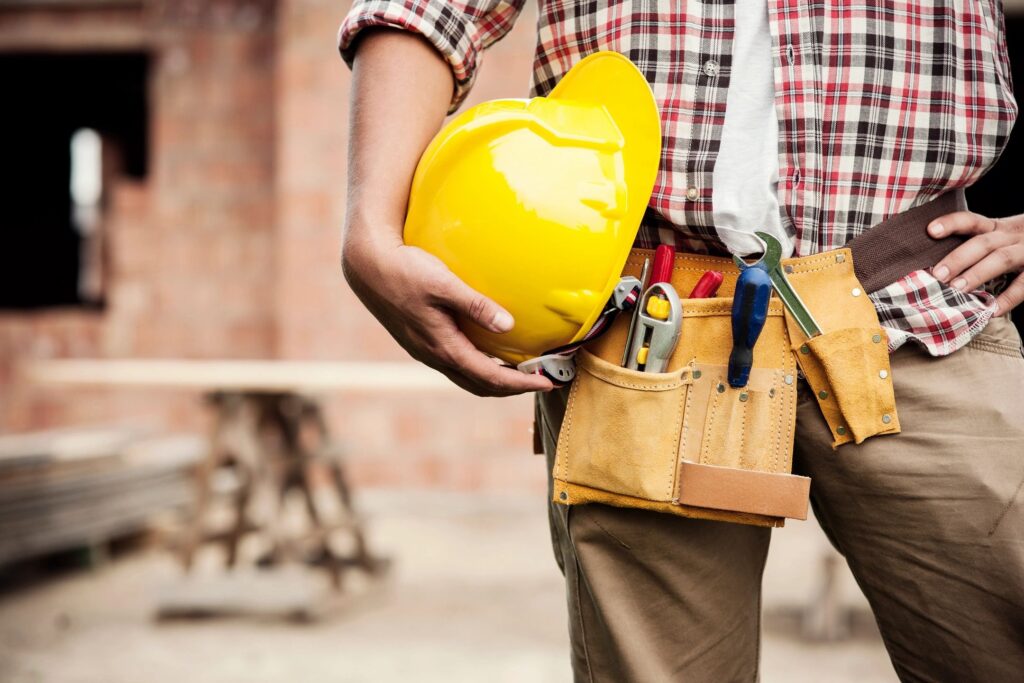 A man holding a yellow hard hat and some tools